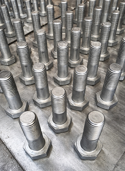 A Large Collection Of Metal Nuts And Bolts Scattered Across A Metal Table Surface.
